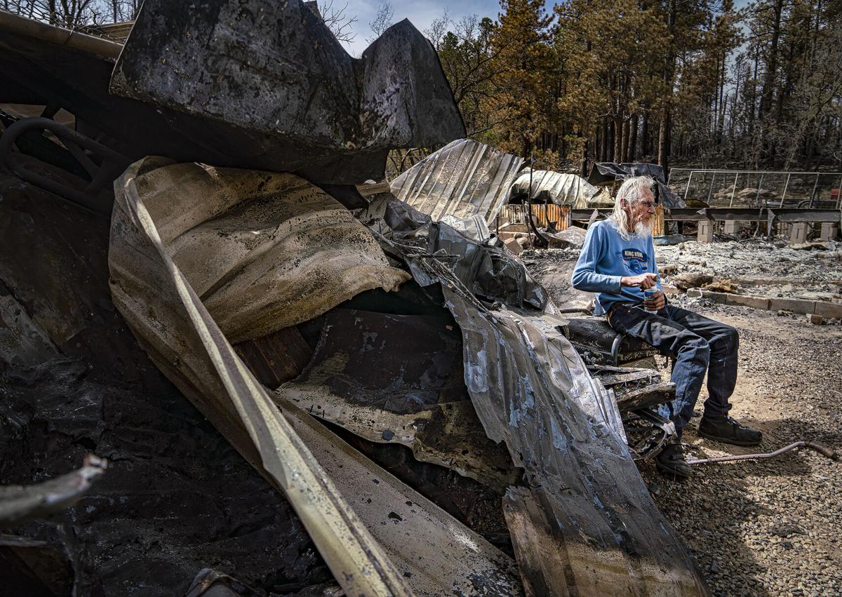 a man sitting amid a property burned in a wildfire