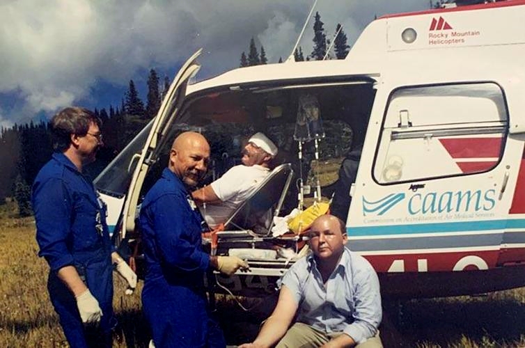 men sit in and stand around a rescue helicopter 